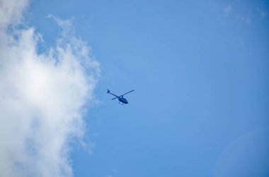 Mavi gökyüzünde beyaz bulutlu sivil helikopter