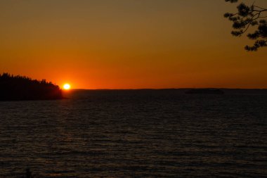 Güneş ufukta batıyor, gün batımında gökyüzü parlıyor. Yaz alacakaranlığının güzel fotoğrafı