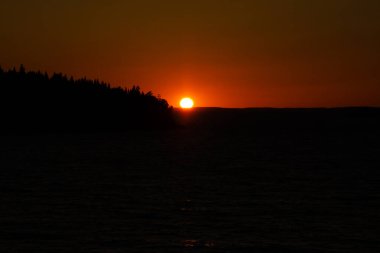 Gün batımında kırmızı-turuncu gökyüzü, ufukta güneş batıyor. Yaz alacakaranlığının güzel fotoğrafı