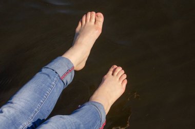 Güneşli bir yaz gününde kotlu çıplak ayaklı bir kız. Yatay yakın plan fotoğraf