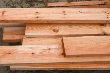 İnşaat alanında yeni tahtalar. Kumda yatan tahtalar. Gri gün.