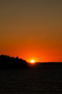 Güneş ufukta batıyor, gün batımında gökyüzü parlıyor. Yaz alacakaranlığının güzel fotoğrafı