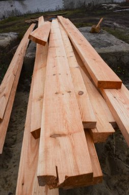 İnşaat alanında yeni tahtalar. Tahtalar çimentoda yatıyor, kumların arasında. Dikey fotoğrafçılık ve seçici odak.