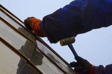 Ortodoks kilisesinin yaldızlı kubbesini birleştiriyorum. Eldiven ustası, plastik bir çekiçle kubbenin parçalarını topluyor..