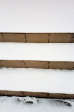 Basamaklar beyaz karla kaplı. Fayansların üzerinde kar var. Dikey fotoğraf, doku.