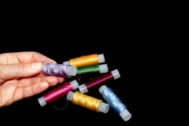 Dişi ellerde iplik izleri var. Nakış işlemek için ipek iplikler. Sarı, mavi, yeşil, pembe, mor ve leylak derileri. Siyah arkaplan.