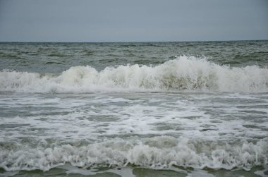 Dalga kıyıya vurdu, beyaz köpük damlaları, yaz bulutlu bir gün, tatil konsepti