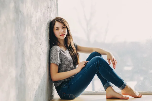 Hermosa chica está soñando junto a la ventana Fotos de stock libres de derechos