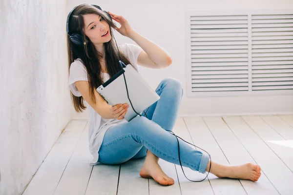 Chica escucha música sentada en el suelo en el estudio. Mientras que cro Imágenes de stock libres de derechos