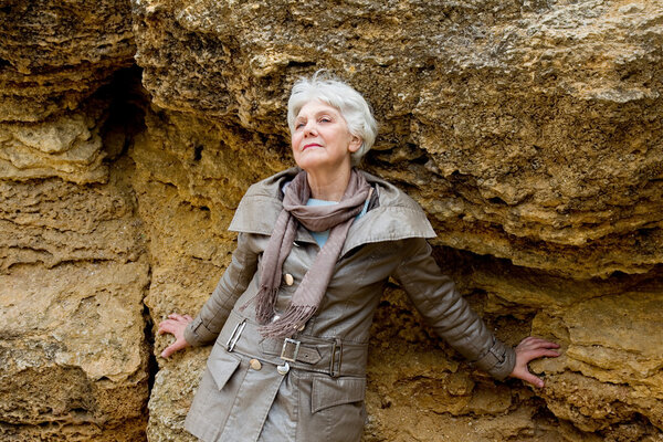 beautiful cute elderly woman on textured stone background looks into the distance