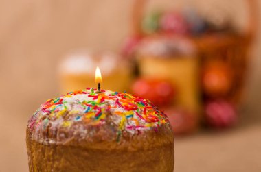 Paskalya pastası. Paskalya pastası ve Paskalya yumurtaları nakış üzerinde duruyor ve yanan bir mum.