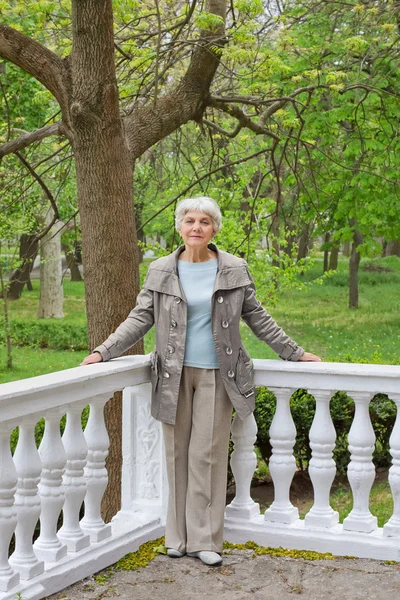 Cute elderly woman senior on the beautiful white verandah in the park — Φωτογραφία Αρχείου