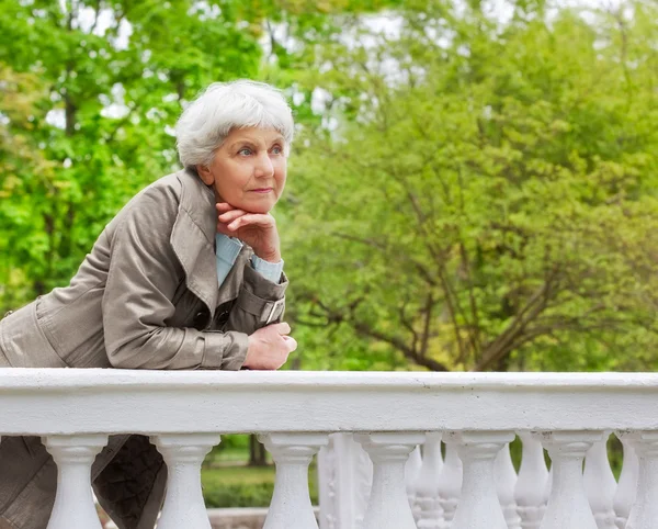 Cute elderly woman senior on the beautiful white verandah in the park — Stok fotoğraf