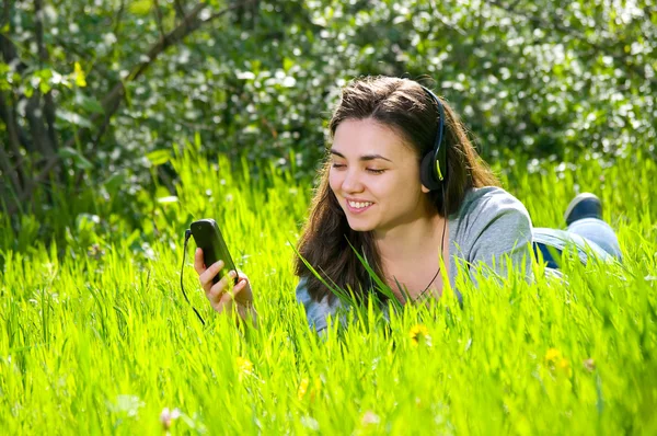Güzel genç kadın kız parkta kulaklık ile doğa üzerinde konuşurken telefon çalar müzik dinlerken