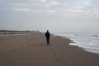 Sahilde yürüyen bir adam var.