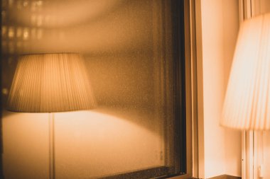 Sıcak ışık ve penceresinde yansıma olan zemin lambası