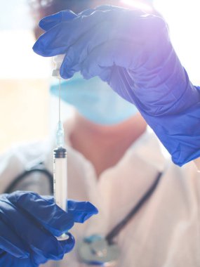 Covid-19 için aşının hazırlanması ön planda ve arka planda bir sağlık çalışanı olan şişe ve şırınga olabilir.