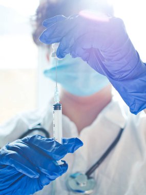 Covid-19 için aşının hazırlanması ön planda ve arka planda bir sağlık çalışanı olan şişe ve şırınga olabilir.