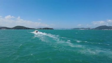 Sürat teknesi Güneydoğu Asya 'daki tropik adaların yakınlarındaki deniz dalgaları boyunca yarışıyor. Hızlı motorlu tekne mavi suda beyaz sprey üretiyor, macera seyahatlerini, deniz ulaşımını ve Vietnam veya Tayland 'da egzotik tatilleri temsil ediyor..