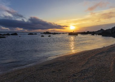 Deniz kıyısında gün doğumu kayalarla