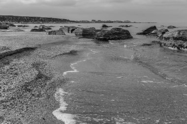 Denizin sığ sularından sonra kıyıda kaya parçaları vardı.