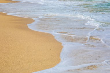 Kumlu bir sahilde köpükle dalgalanan