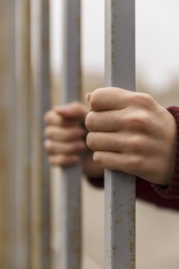 Ellerini parmaklıkların arkasına