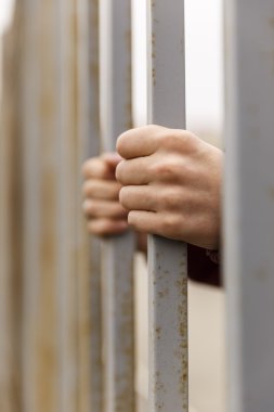 Ellerini parmaklıkların arkasına