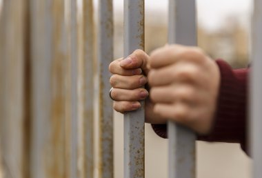 Ellerini parmaklıkların arkasına