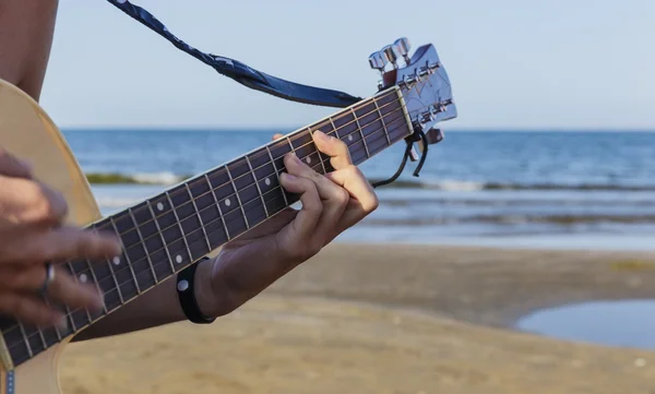 Jovem tocando guitarra acústica na praia — Fotografia de Stock