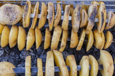 Dilimlenmiş patates ve koymak üzerinde şiş şiş