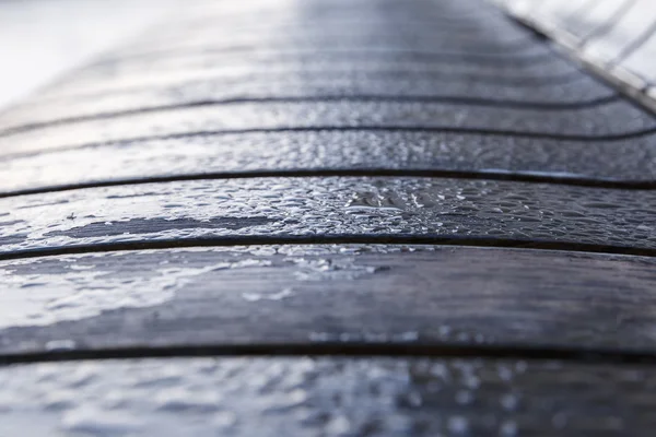 Gotas de rocío matutino en un banco de madera en el parque —  Fotos de Stock