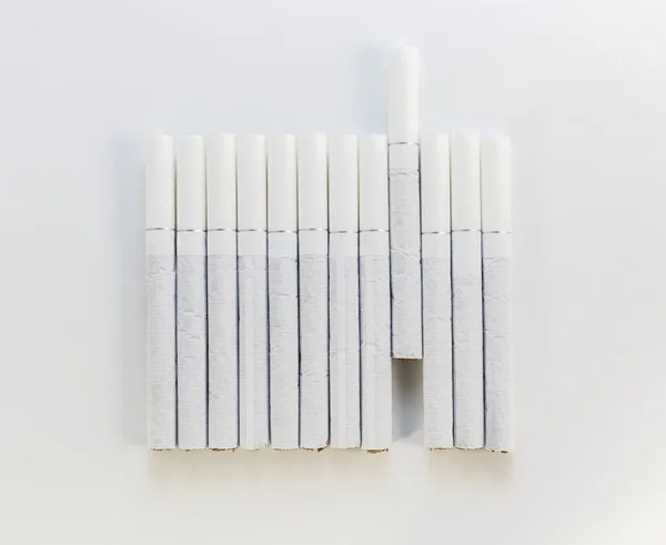 Сигарета с белым фильтром, выложенным в ряд на белом спинке — стоковое фото