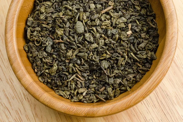 Tè verde, foglie secche, su fondo di legno — Foto Stock