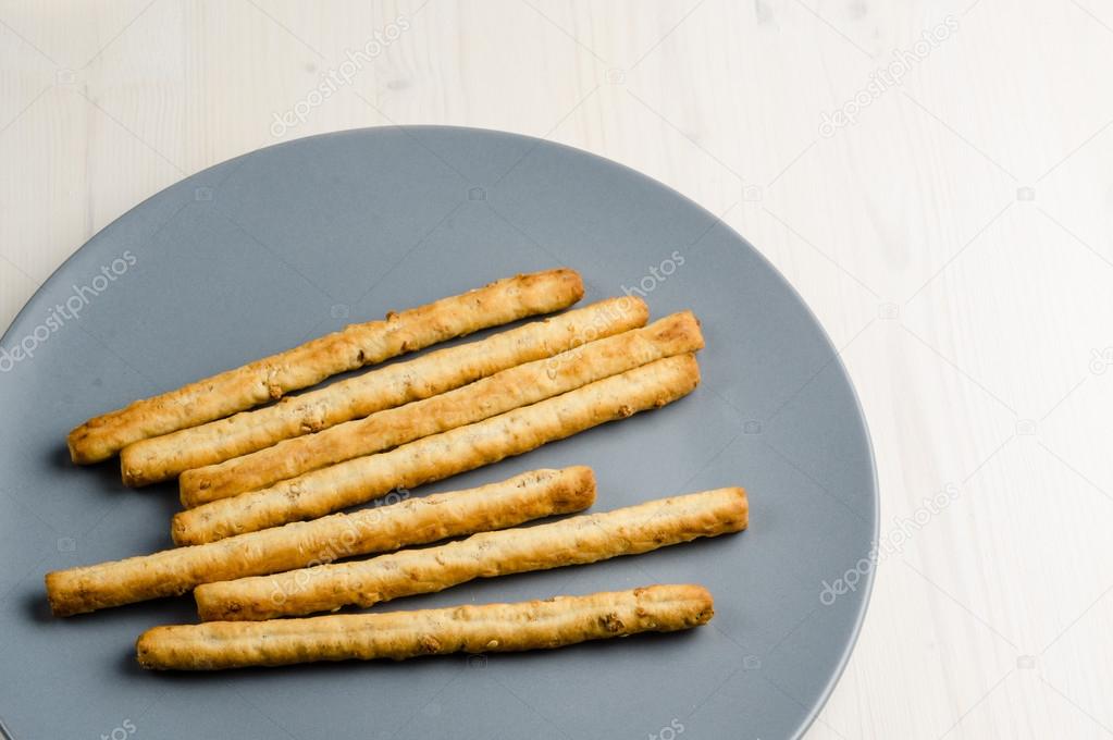 rustic breadsticks in a dish on wood table, close up, background