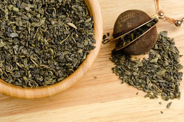 Ahşap arka plan üzerinde filtreli yeşil çay, kurutulmuş yaprakları