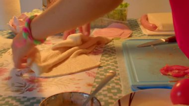 Bu yemek pişirme videosunda, bir çocuk sıfırdan tortilla pişirirken, bir kişi taze malzemeleri karıştırıyor, yemek için renkli bir aşama hazırlıyor.