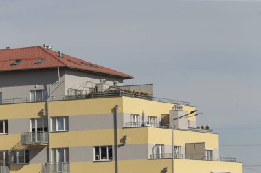 katmanlı çatıları olan güneşli daireler, güneşli sarı teraslar sakin bir yerleşim yeri manzarası oluşturur, sabah ışıltısı katmanlı çatıları aydınlatır ve huzurlu ufuk çizgisindeki sarı apartman terasları