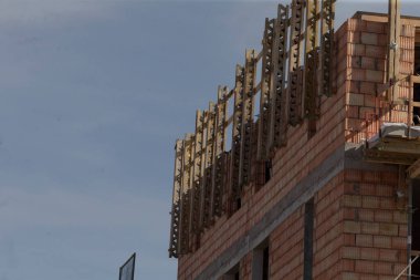 Tamamlanmamış üst kat ahşap işleme ve güvenlik rayları çerçeve pencere açıkları, ham tuğla yükseltileri ve geçici canlandırma inşaat alanı dokusu ve yüksek açılı mimari detay oluşturur