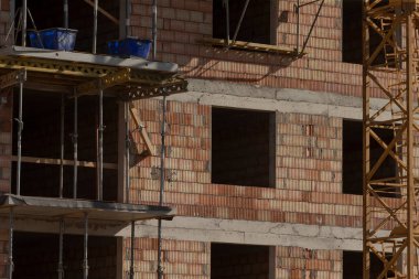 Endüstriyel tuğla bina, inşaat demiri ile tamamlanmamış tuğla yapı, açık pencere alanları ve gölgelerden oluşan çıplak tuğla kabuk, iç gölgeleri ve açık pencere alanlarını ortaya çıkaran sert tuğla cephe