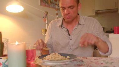 Adam makarna yiyor, adam huzur içinde makarnanın tadını çıkarıyor, orta yaş erkeği evde rahat rahat makarnanın tadını çıkarıyor, orta yaşlı adam rahatlıyor ve evinde lezzetli makarnanın tadını çıkarıyor.