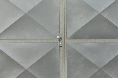 Merkezi sürgülü elmas desenli metal kapı, endüstriyel gümüş paneller ve kaynaklı dikişler, soğuk metalik parıltı ve ince yansımalar, sağlam güvenli görünüş, yakın perspektif vurgu simetrisi