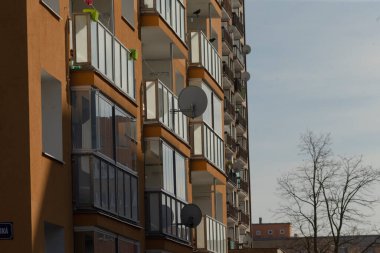 şehir balkonu, tabaklar ve ağaçlarla dolu balkonlar, uydu antenleri ve siluetlerin yer aldığı apartman balkonları, uydu çanaklarıyla donatılmış ortak barınma balkonları ve sakin şehir manzarası
