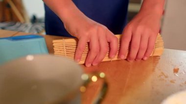 Şefin suşi sarması için kullandığı bambu hasırı sıcak mutfak masasında salatalıklı taze suşi hazırlıyor.