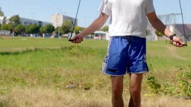 Adam dışarıda egzersiz yapıyor, adam dışarıda ip atlama eğitimi alıyor, adam açık alanda ip atlama egzersizi yapıyor, adam ip atlama egzersizi sırasında ritmini koruyor.