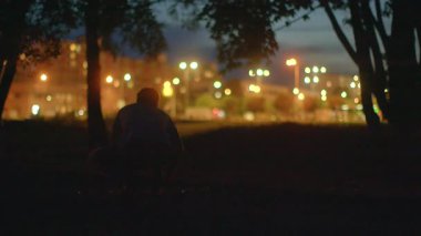 Bir adamın ağacın altında hayatı yansıttığı sakin bir parkta sakin bir gece. Gölgeler uzadıkça, doğanın sakinliğini somutlaştıran ve gizemi çağrıştıran bir figür geziniyor.