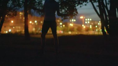 Bu video, hareketli bir gece parkı sergiliyor. Bir adam kararlı bir şekilde koşar, diğeri halat atlayıp çeviklik gösterirken, bir çift yıldızların altında romantik bir anı paylaşır.