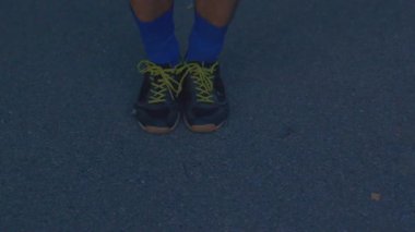 Atletik ayakkabılar ve asfalta bağlayan dantel, bağcıklara diz çöken beyaz atlet ve esneyen dana ve ayak bileği, ön koşu.