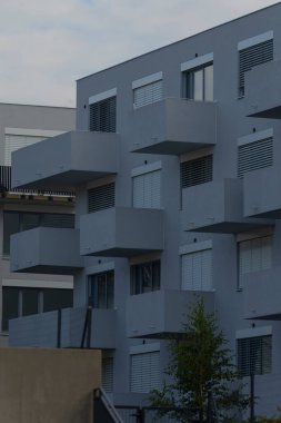 Gri modern bloktaki geometrik balkonlar güçlü çizgiler oluşturuyor. sade mimari çalışma ile kübik