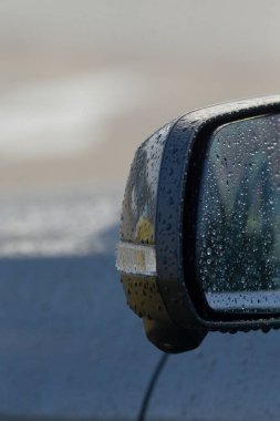 yağmur lekeli yan ayna kehribar göstergesi ışığı gösteriyor, ıslak yol kenarlı atmosferli banliyö güvenliği teması